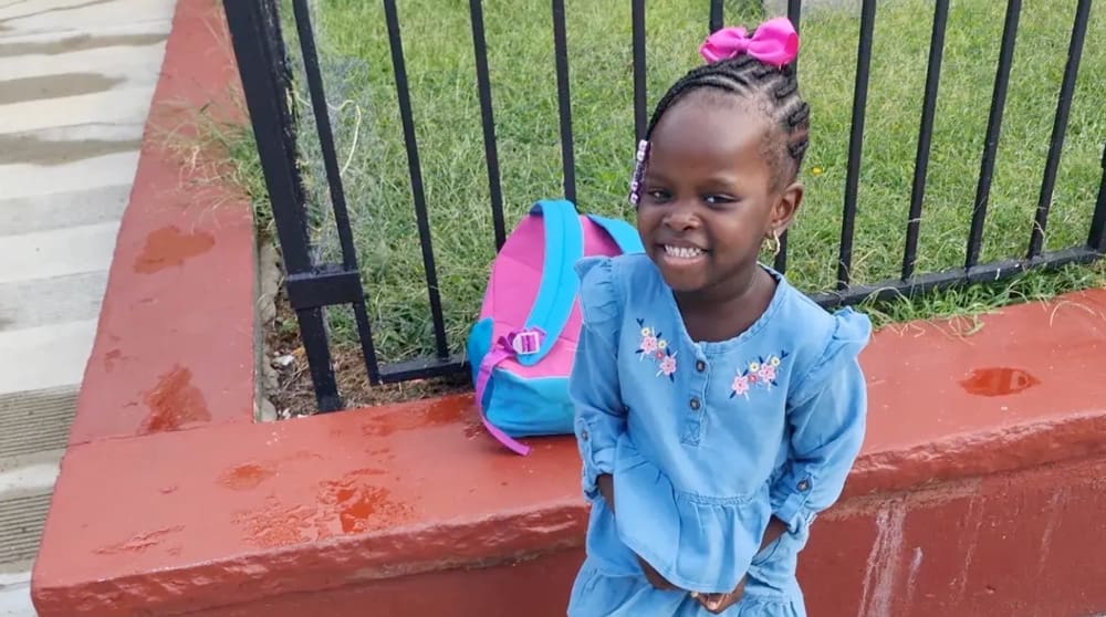 Jadori on the street corner smiling with her backpack