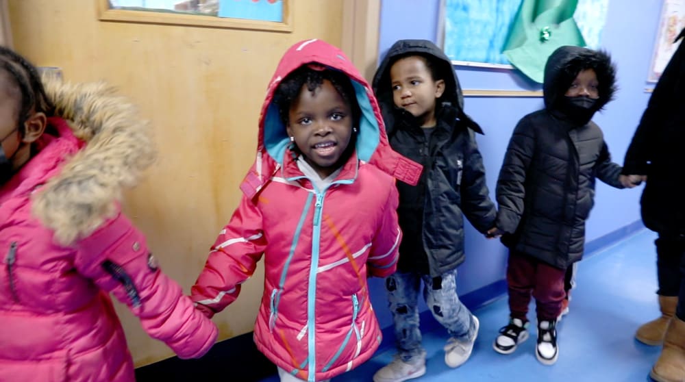 Jadori in the school hallway holding hands with her classmates